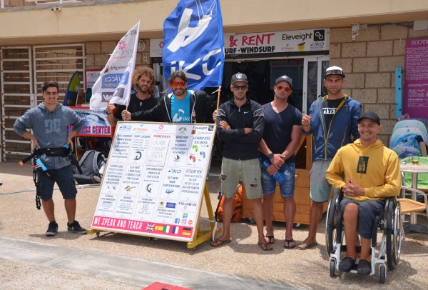 A group of people with 2 IKO flags. One of the group is a wheelchair user.