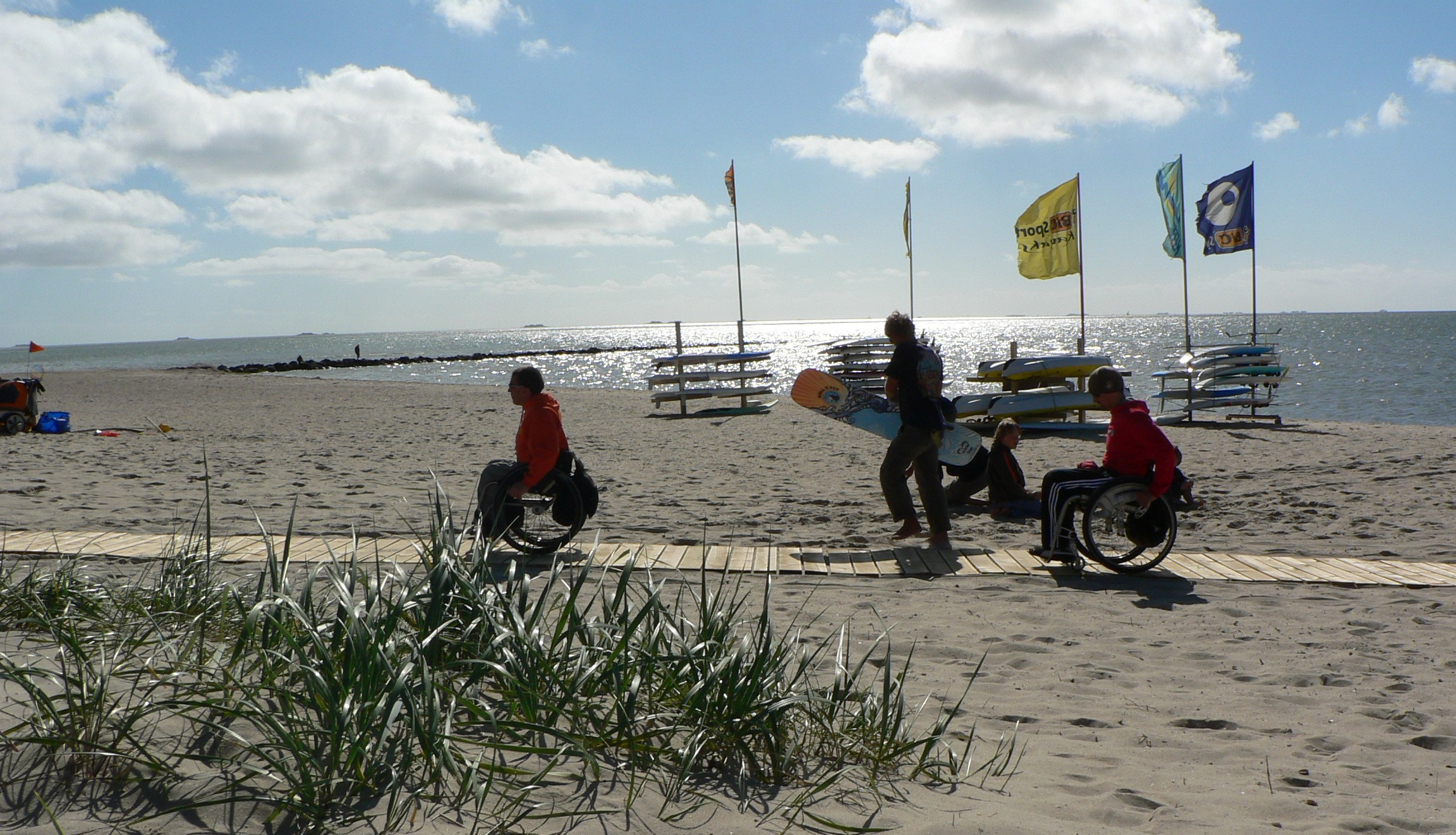 2 wheelchair-users on a ramp on the beach.