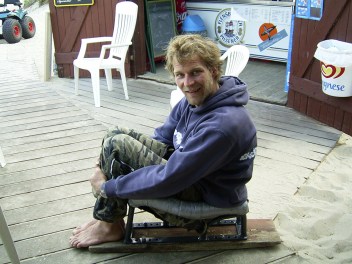 A man sits in kiteboarding seat on land.