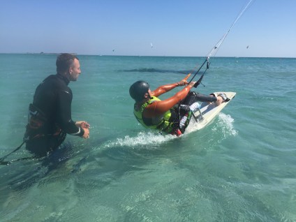 A sitting kiteboarder during the start. Behind him the kite instructor has just let go of the board.