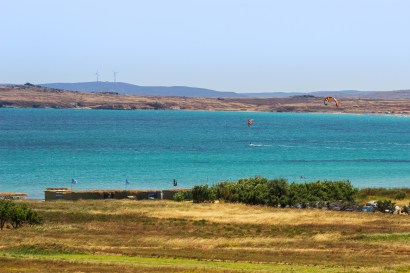 The steppe of Keros with some olive trees. In the background the turquoise bay with two kites.